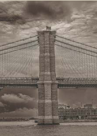Hängebrücke mit steinernem Brückenpfeiler über einem Fluss unter bewölktem Himmel. Fotograf Marco Frei 2026 in New York für decira.