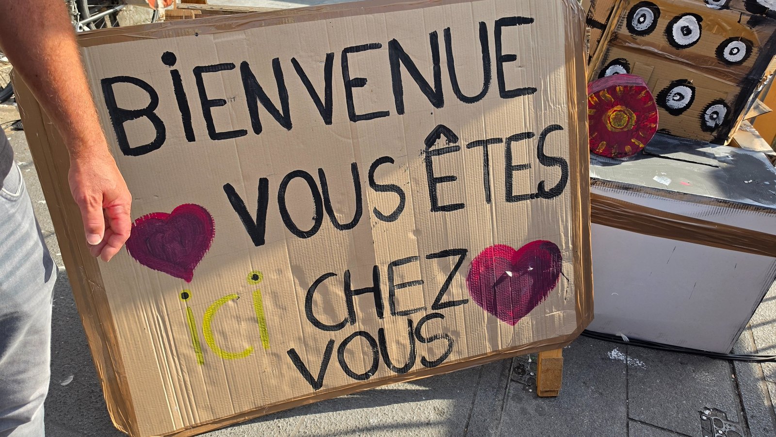 Handgemaltes Schild mit der französischen Aufschrift „Bienvenue, vous êtes chez vous“ – Symbol für Willkommen und Zugehörigkeit.